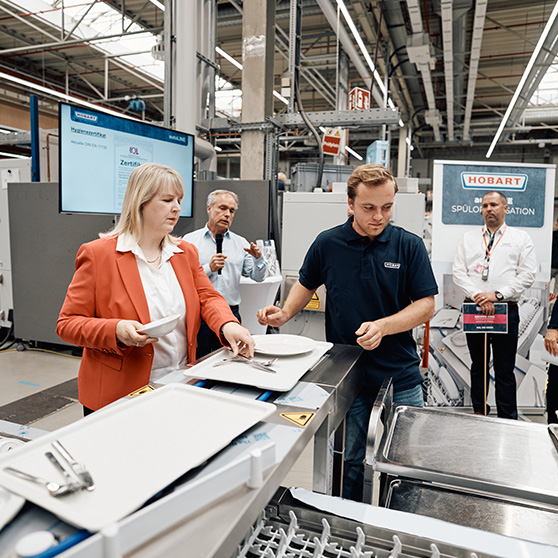 Präsentation eines HOBART Systems mit Teilnehmern an einem Förderband in industrieller Umgebung