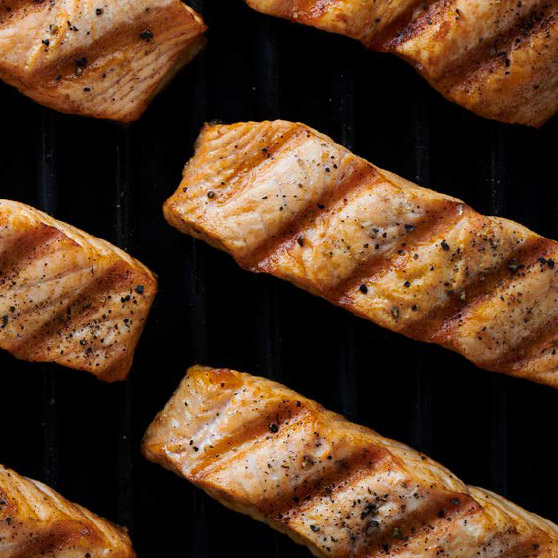 Gegrillte Lachsfilets mit deutlichen Grillstreifen und Gewürzen – perfekt gegart mit dem CHEF'S COMBI von HOBART für gleichmäßige und professionelle Grillergebnisse.