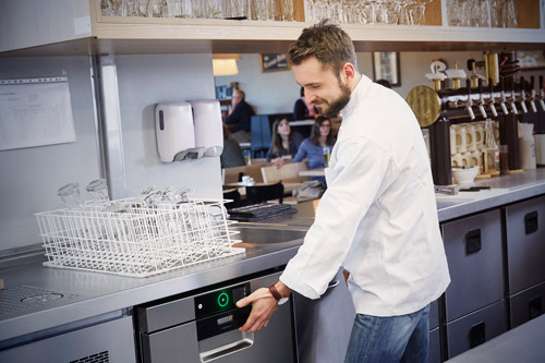 Barkeeper öffnet die Gläserspülmaschine unter der Theke