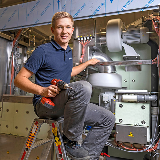 Person arbeitet mit Akkuschrauber an einer industriellen Maschine