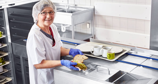  Detailansicht der FLOW Line mit integrierter Speisereste-Entsorgungstechnik für hygienische Entfernung von Essensresten und automatisiertem Fördersystem für Tabletts und Geschirr in professionellen Großküchen.