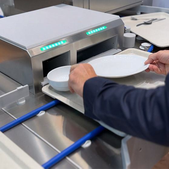 Nahaufnahme des HOBART SMART LOAD Beladungssystems mit ergonomischer Einlegung von Tellern und Schalen auf einem Tablett in die vorgesehenen Öffnungen für automatisierte Weiterverarbeitung in der professionellen Spülstraße.